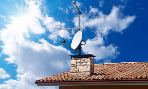 Satellite dish and TV antennas on the house roof with a beautiful blue sky